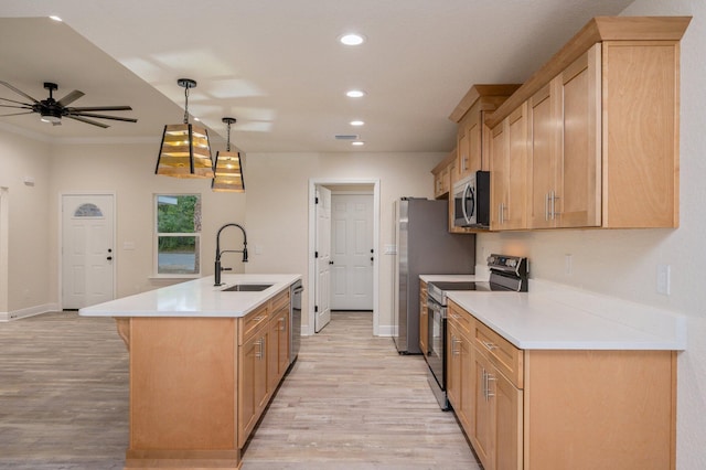 kitchen with a sink, light wood-style floors, appliances with stainless steel finishes, and a center island with sink