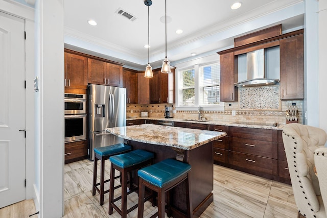 kitchen featuring visible vents, a sink, stainless steel appliances, a kitchen bar, and wall chimney exhaust hood