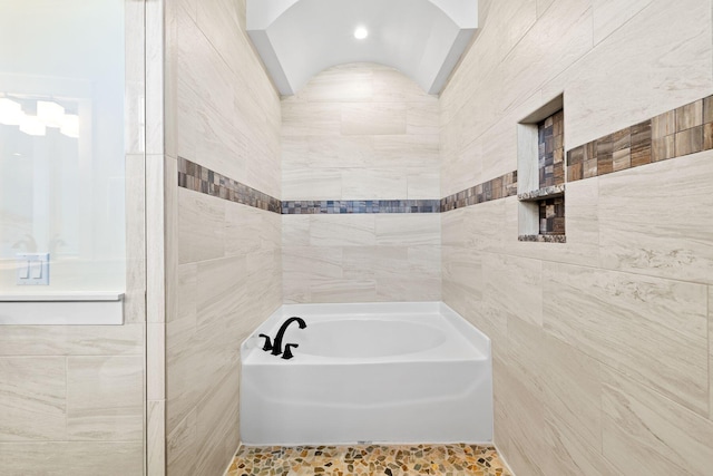 full bath with tile walls and a bath