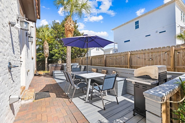 deck featuring outdoor dining area, a fenced backyard, and a hot tub