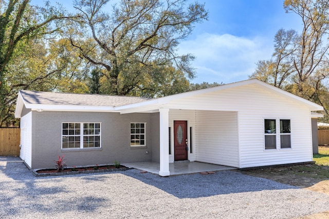 view of front of house featuring a patio, fence, and brick siding