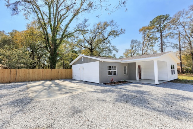 single story home featuring gravel driveway and fence