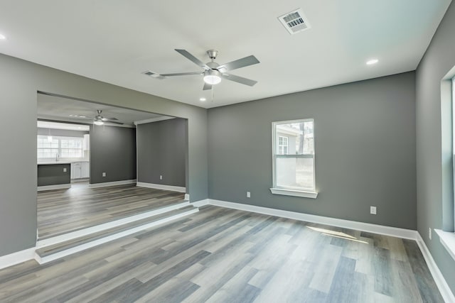 empty room featuring wood finished floors, visible vents, and baseboards