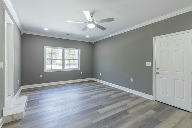 unfurnished room featuring visible vents, crown molding, baseboards, wood finished floors, and a ceiling fan