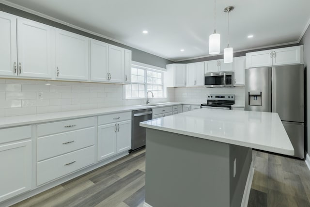 kitchen featuring wood finished floors, stainless steel appliances, decorative backsplash, hanging light fixtures, and white cabinets