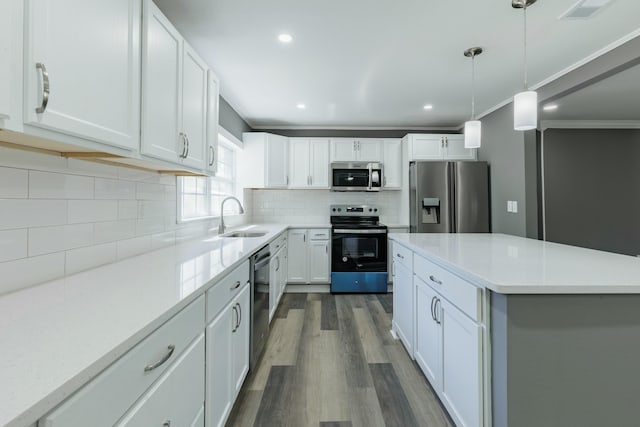 kitchen with tasteful backsplash, dark wood-type flooring, light countertops, appliances with stainless steel finishes, and a sink