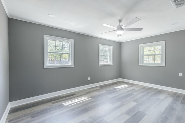 spare room featuring visible vents, wood finished floors, crown molding, baseboards, and ceiling fan