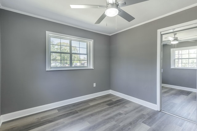 unfurnished room featuring ceiling fan, baseboards, wood finished floors, and crown molding