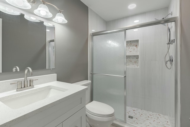 bathroom with a shower stall, toilet, and vanity