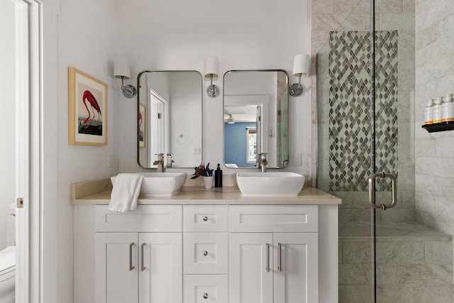 bathroom featuring double vanity, a shower stall, toilet, and a sink