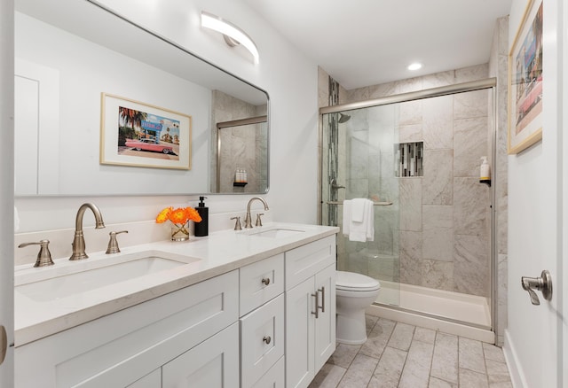 full bathroom with double vanity, a shower stall, toilet, and a sink