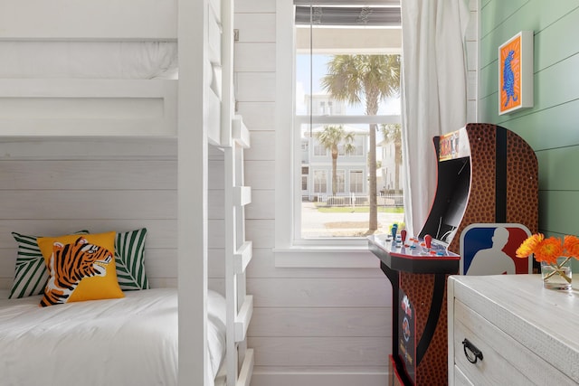 bedroom featuring multiple windows and wooden walls