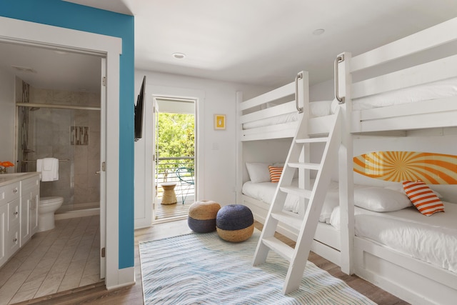 bedroom with connected bathroom, baseboards, light wood-style flooring, and access to exterior