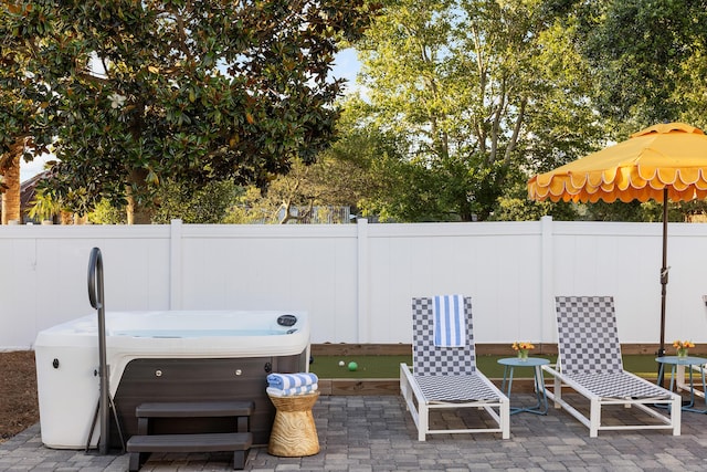 view of patio / terrace with a hot tub and fence