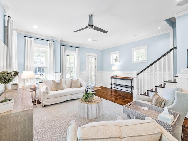 living area featuring stairs, crown molding, wood finished floors, and ceiling fan