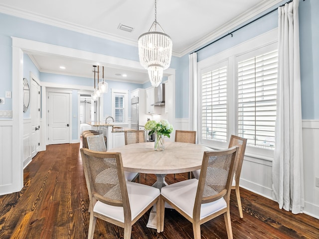 dining room featuring a wainscoted wall, a notable chandelier, dark wood-style flooring, and ornamental molding