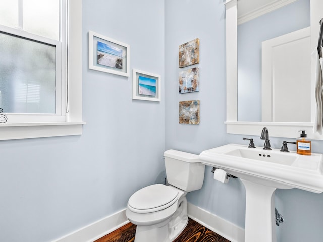 bathroom with toilet, wood finished floors, baseboards, and a sink