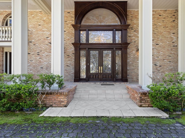 view of exterior entry featuring brick siding and covered porch