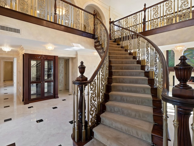 stairway featuring visible vents, french doors, a towering ceiling, and ornamental molding