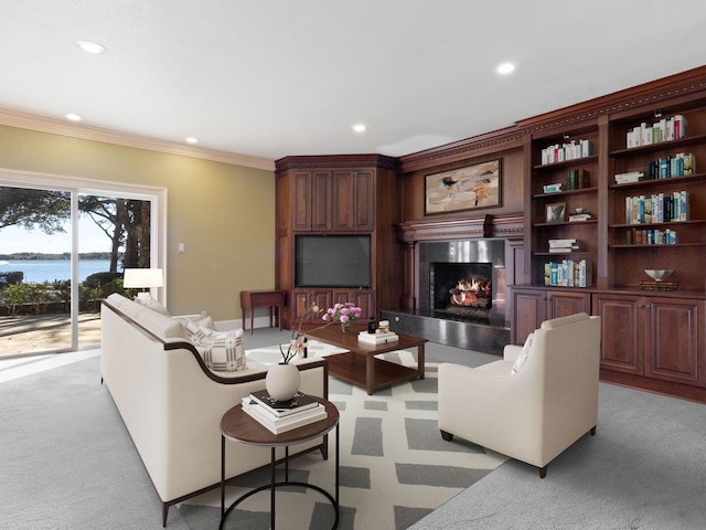 living area with a water view, a glass covered fireplace, recessed lighting, crown molding, and light colored carpet