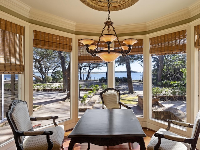 sunroom / solarium featuring a notable chandelier, a healthy amount of sunlight, and a water view