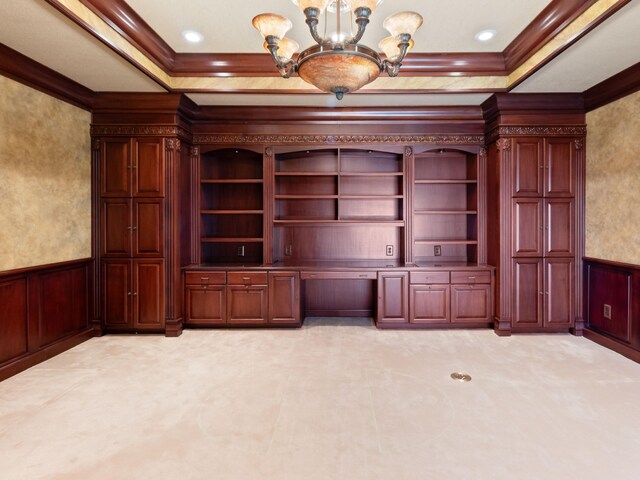 unfurnished office featuring a wainscoted wall, a raised ceiling, crown molding, and an inviting chandelier