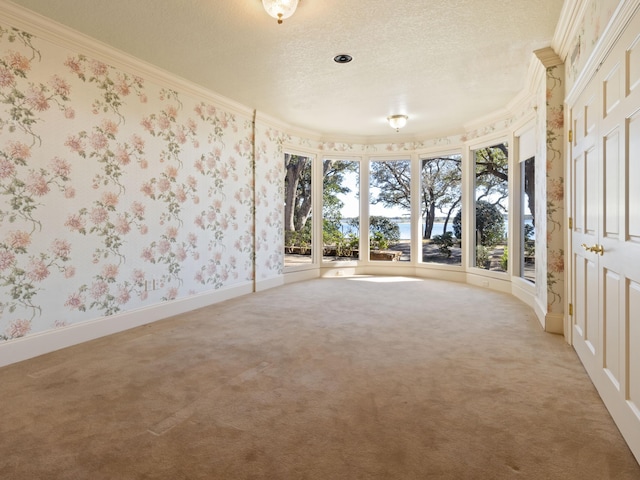 spare room with wallpapered walls, crown molding, a textured ceiling, and light carpet