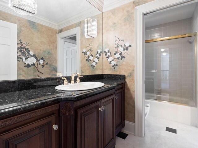 bathroom featuring combined bath / shower with glass door, toilet, ornamental molding, and vanity