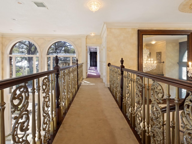 hall featuring an upstairs landing, visible vents, light carpet, and ornamental molding