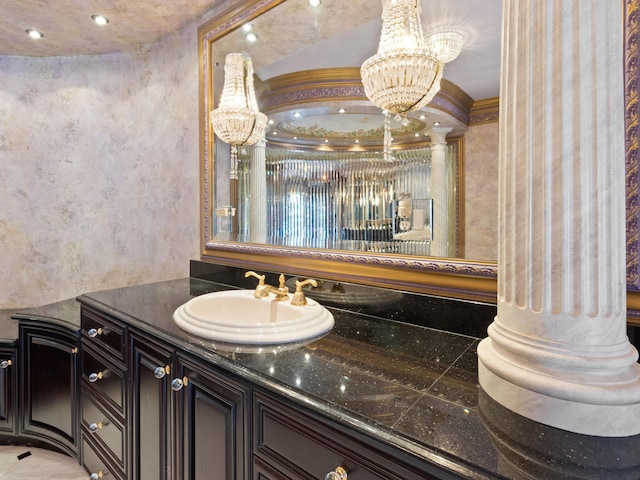 bathroom featuring recessed lighting, vanity, an inviting chandelier, and decorative columns