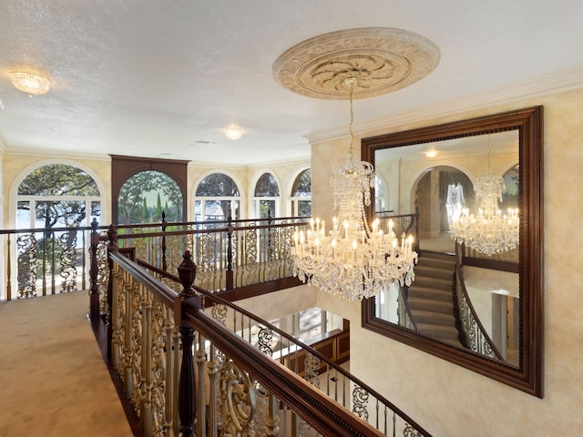 hall with a wealth of natural light, an upstairs landing, carpet, and a chandelier