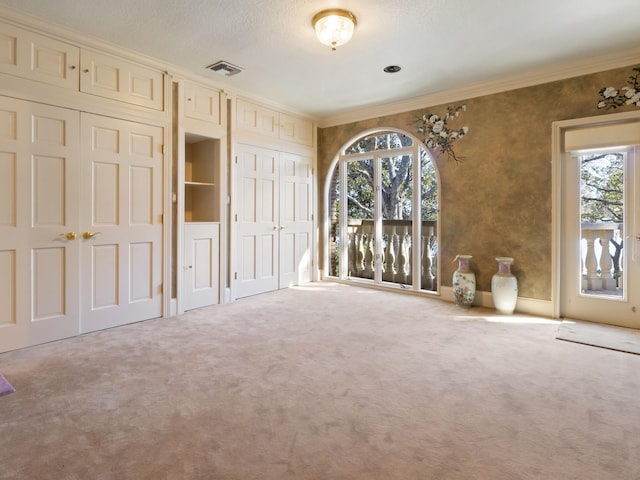 unfurnished bedroom with visible vents, carpet flooring, and crown molding