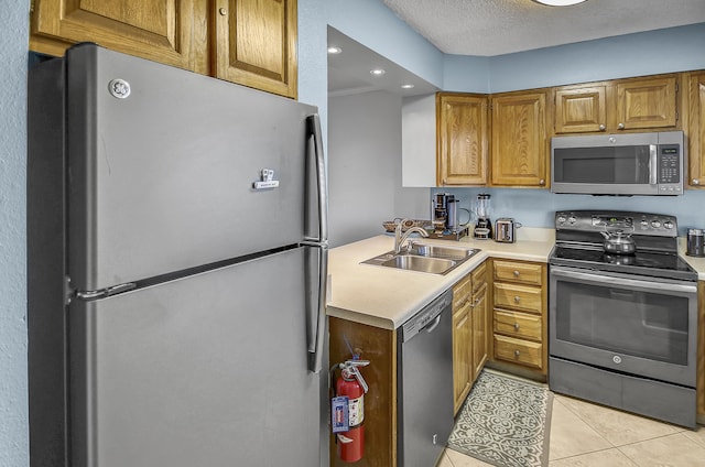 kitchen with light tile patterned floors, a sink, stainless steel appliances, light countertops, and a textured ceiling