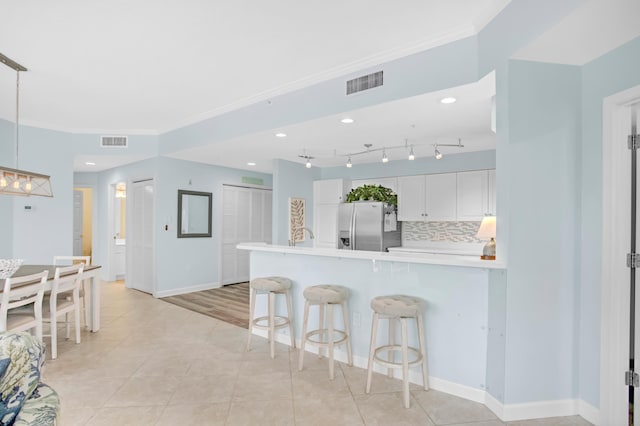 kitchen with visible vents, a breakfast bar area, crown molding, and stainless steel fridge with ice dispenser