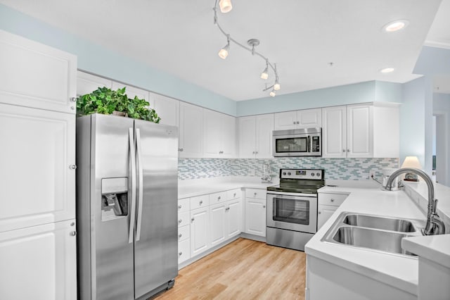 kitchen with decorative backsplash, appliances with stainless steel finishes, light wood-style floors, white cabinets, and a sink