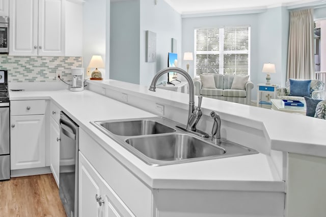 kitchen featuring light wood-style flooring, a sink, open floor plan, dishwasher, and tasteful backsplash