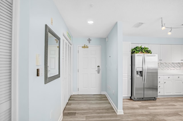 hallway with baseboards, visible vents, and light wood finished floors