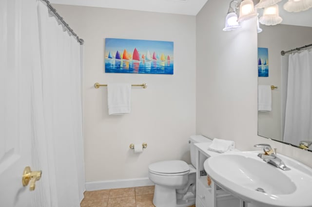 bathroom with tile patterned flooring, toilet, baseboards, and a sink