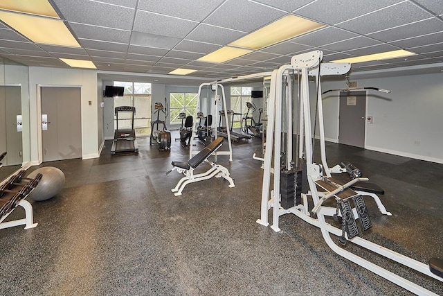 gym featuring baseboards and a drop ceiling