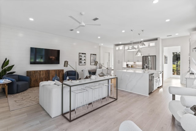 living room with visible vents, recessed lighting, light wood-type flooring, and a ceiling fan