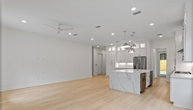 kitchen with visible vents, a spacious island, stainless steel appliances, light wood-style floors, and white cabinets