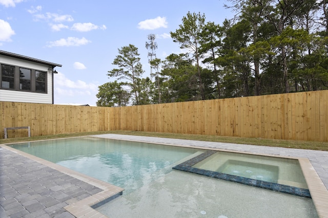 view of pool with a fenced backyard and a pool with connected hot tub