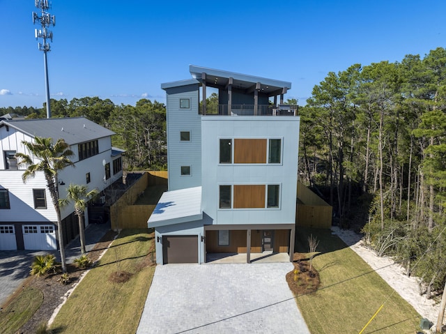 contemporary home featuring a garage, a front lawn, decorative driveway, and a balcony