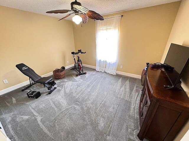 exercise room with ceiling fan, baseboards, dark colored carpet, and a textured ceiling