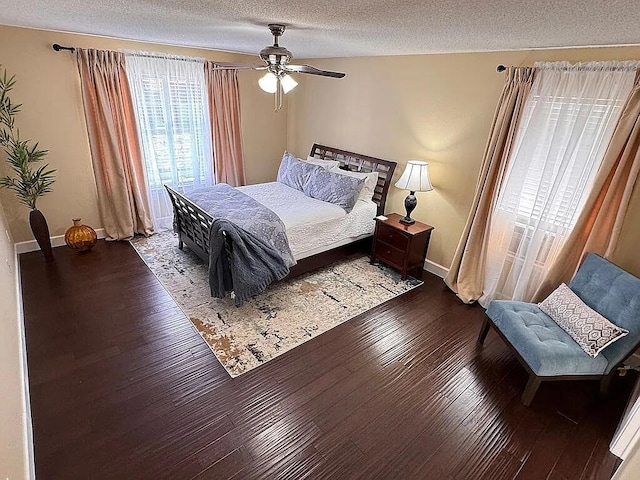 bedroom featuring ceiling fan, a textured ceiling, baseboards, and hardwood / wood-style floors