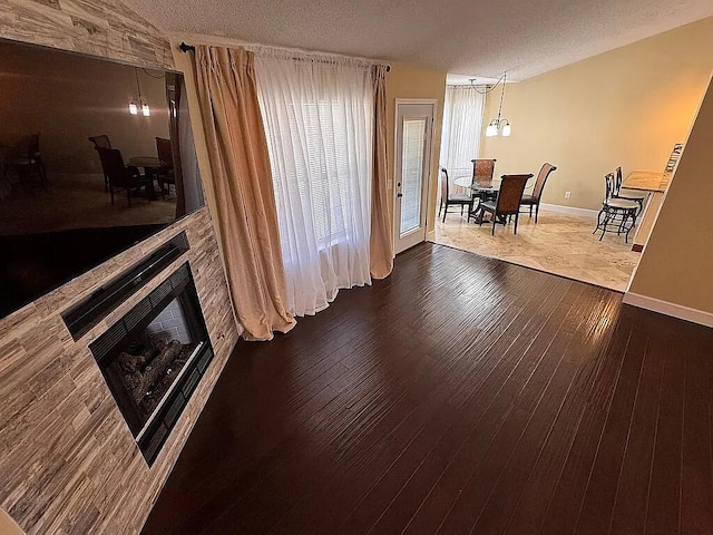 interior space featuring baseboards, a fireplace, dark wood-style flooring, and a textured ceiling