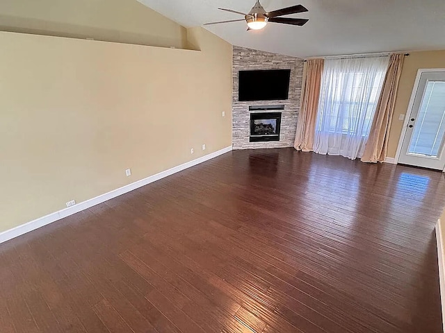 unfurnished living room with a stone fireplace, lofted ceiling, dark wood finished floors, and ceiling fan