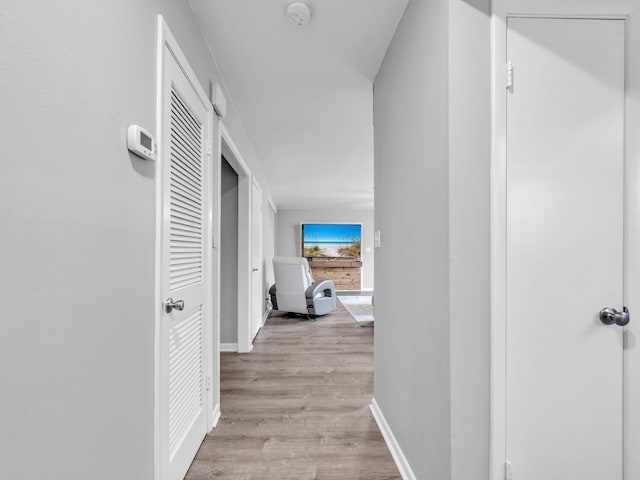 corridor featuring baseboards and light wood finished floors