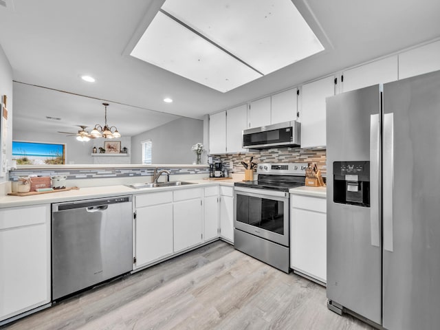 kitchen featuring decorative backsplash, appliances with stainless steel finishes, white cabinetry, and a sink