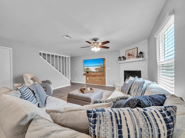 living area with ceiling fan, baseboards, stairway, a fireplace, and wood finished floors